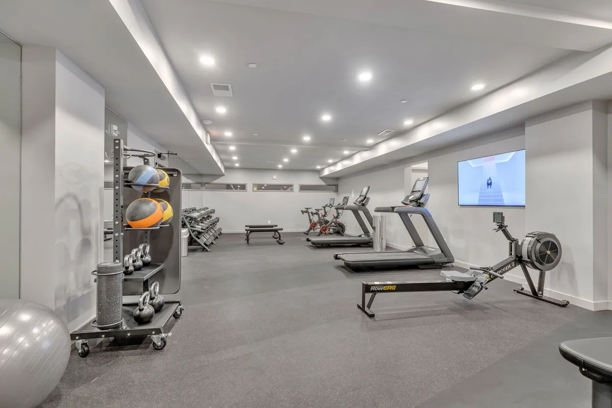 A well-equipped gym features modern exercise equipment and bright, motivational decor. The space is designed for both individual workouts and group fitness, with exercise balls, weights, and a display monitor. The environment is clean and professionally maintained, catering to guests who value wellness during their stay.
